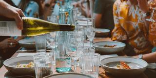 Eine Person schenkt Wein in ein Glas auf einem gedeckten Tisch ein (Foto: Pixabay / elli_kh)