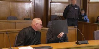 Landgericht Saarbrücken. Der Angeklagte sitzt neben seinem Anwalt und verdeckt sein Gesicht mit einer Mappe. (Foto: SR)