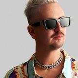 Robin Schulz Haare sind kurz und blond gefärbt, er trägt eine Sonnenbrille und ein kurzes Hemd. Er steht vor grauem Hintergrund und schaut mit neutralem Gesichtsausdruck zur Seite. (Foto: SR)
