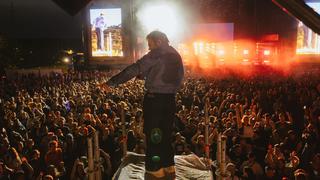 Ein Sänger steht auf einem Turm, im Hintergrund ist eine Bühne und Publikum zu sehen (Foto: MxM Photo)