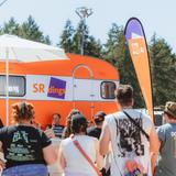 Leute stehen vor einem orangenen Wohnwagen. (Foto: MxM Photo)