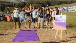 Eine Gruppe von Menschen steht nebeneinander. Im Vordergrund ist ein ausgerollter lila Teppich zu sehen. (Foto: MxM Photo)