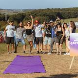 Eine Gruppe von Menschen steht nebeneinander. Im Vordergrund ist ein ausgerollter lila Teppich zu sehen. (Foto: MxM Photo)