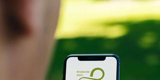 Die Saarland App auf einem Smartphone (Foto: CardMapr.nl/unsplash, Screenshot/App, Bildcollage: SR/Knöbber)