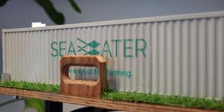 Logo der Seawater Cubes GmbH auf dem Tisch-Modell eines Seewasserfischzuchtcontainers (Foto: SR)