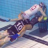 Mehrere Personen befinden sich in einem Schwimmbecken unter Wasser und schwimmen mit einem Ball auf einen Korb am Grund des Beckens zu. (Foto: IMAGO)