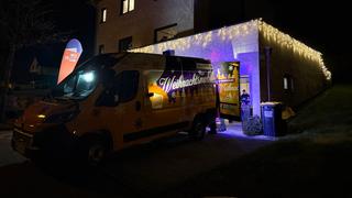 Ein Auto parkt vor einer Garage, die mit Lichterketten geschmückt ist. (Foto: UNSERDING)