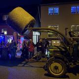 Ein Traktor mit einem Heuballen steht vor einem Platz mit Leuten. (Foto: UNSERDING)