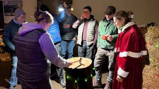 ein Kreis von Leuten steht um einen Holzblock. (Foto: UNSERDING)