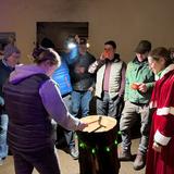 ein Kreis von Leuten steht um einen Holzblock. (Foto: UNSERDING)