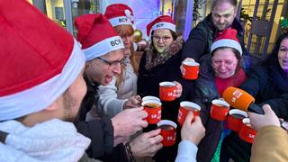 Ein Kreis von Leuten stößt mit gefüllten Tassen an. (Foto: UNSERDING)