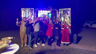 Menschen stehen vorm beleuchteten Weihnachtsmobil und freuen sich (Foto: UNSERDING)