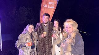 Mehrere Menschen stehen in dicken Pelzmänteln draußen. (Foto: UNSERDING)