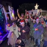 Eine Gruppe von Menschen steht mit Weihnachtsmannmützen neben dem Weihnachtsmobil und wirft fröhlich die Hände in die Luft. (Foto: UNSERDING)