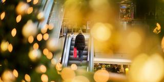 Eine Frau beim Weihnachtsshopping auf einer Rolltreppe (Foto: dpa)